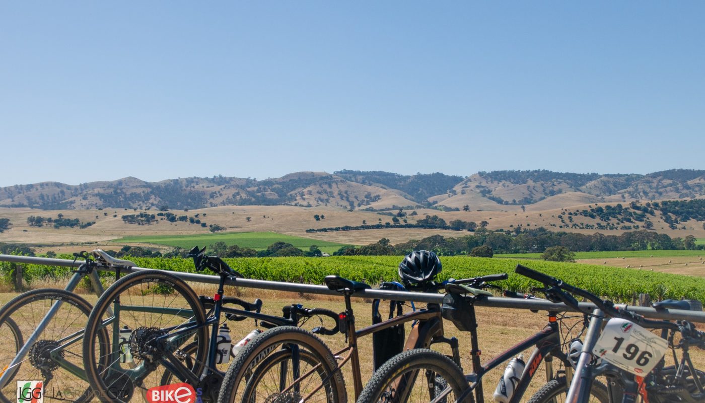 Several bicycles parked at a rack overlook green fields and rolling hills beneath a clear blue sky.